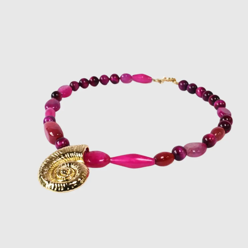"Handcrafted necklace with vibrant fuchsia gemstone beads and gold spiral shell pendant – coastal statement jewelry for women"